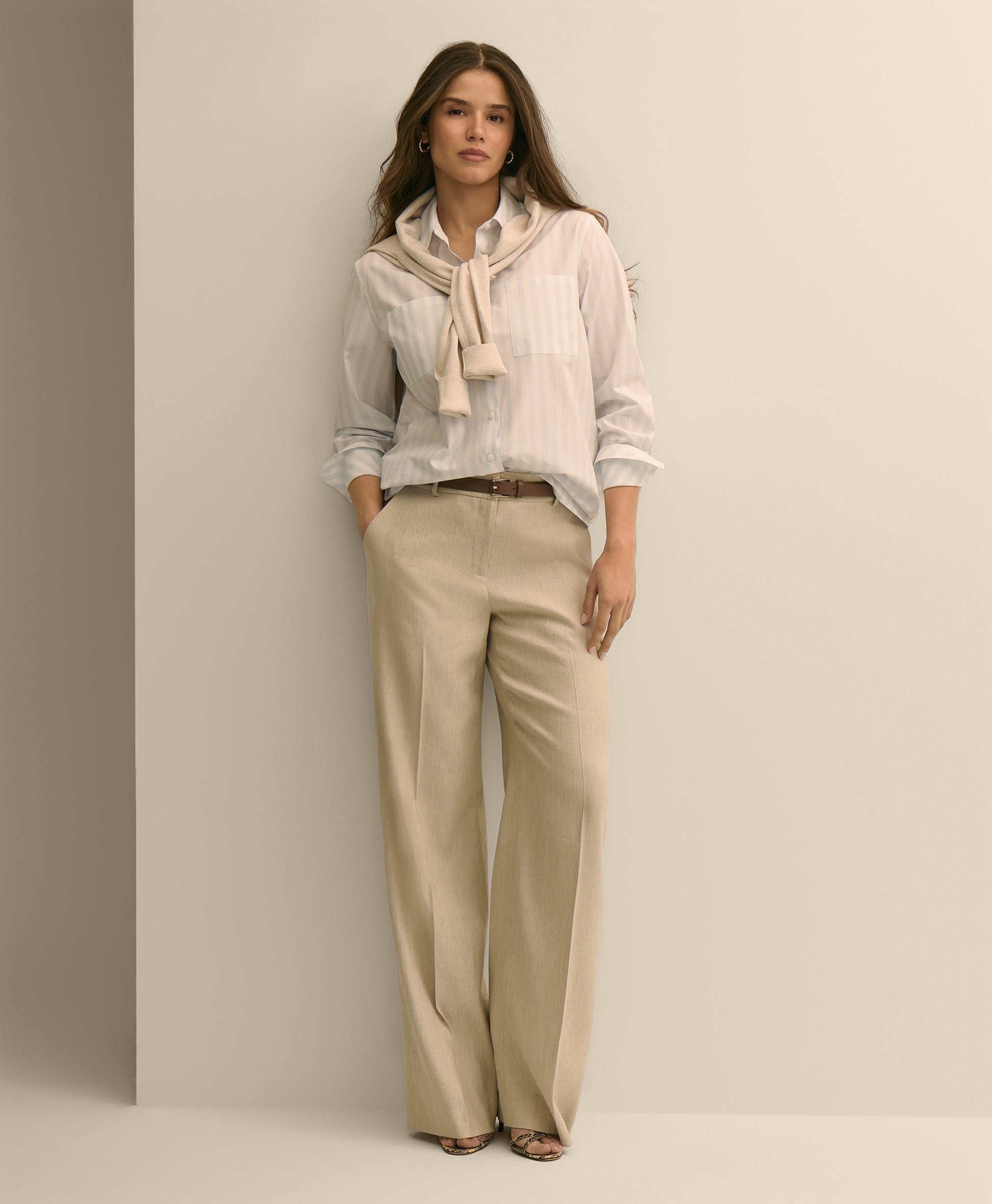 Woman wearing a light-colored blouse with a scarf and beige pants