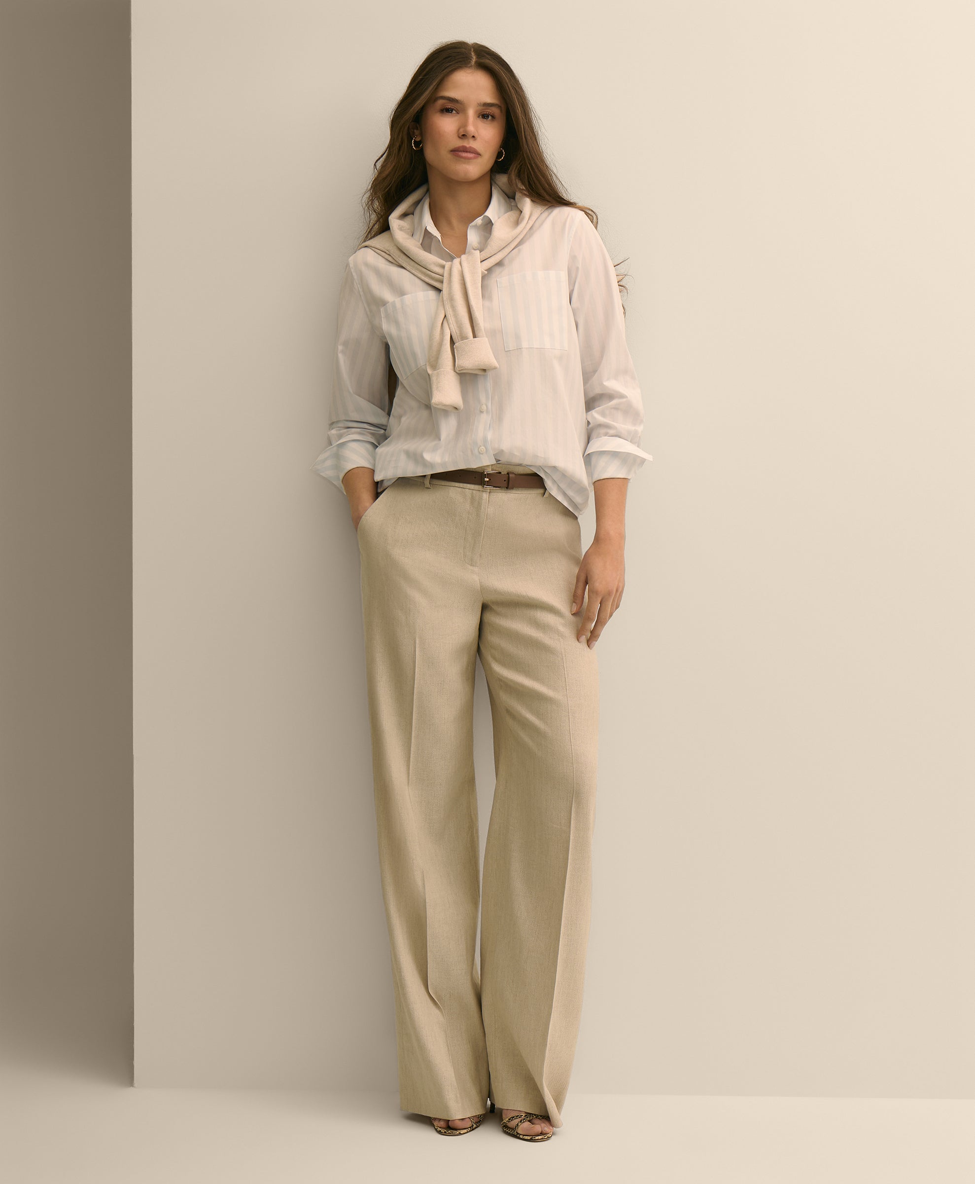 Woman wearing a light-colored blouse with a scarf and beige pants